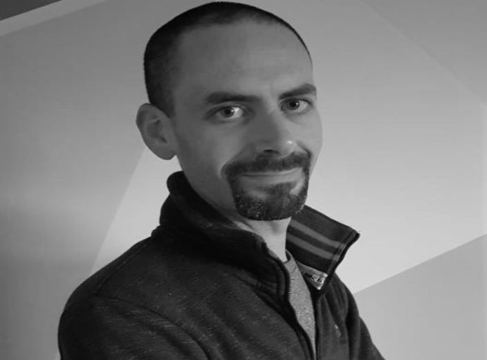 A headshot of Dr. Oliver Treacy in black and white, with a white background