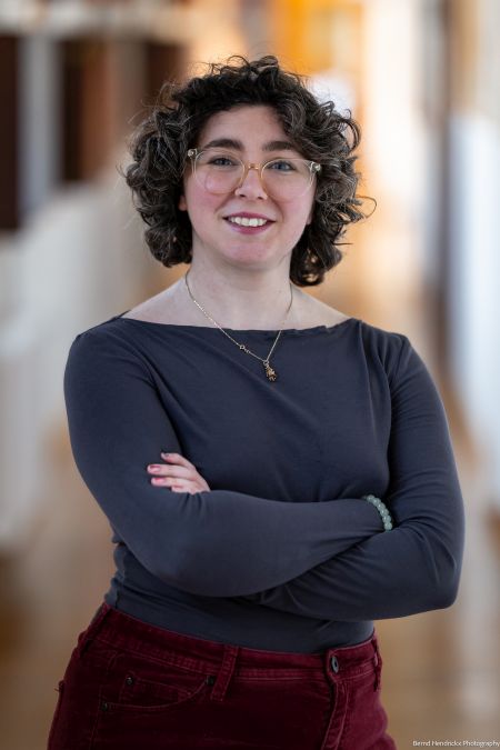 Mairead Casey posed with folded arms in grey top and red pants